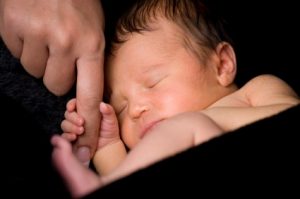 A photo of a baby holding its mother's finger: attachment
